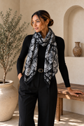 Juodai baltas moteriškas šalikas su paisley ir augaliniu raštu, pagamintas iš 80 % viskozės ir 20 % medvilnės, 85 × 180 cm dydžio, minkštas, jaukus ir elegantiškai krentantis.