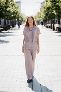 Light lilac linen women's suit consisting of a short-sleeved blouse with decorative pleats around the neckline and down the front, paired with loose-fitting linen trousers. Kišenės tiek palaidinėje, tiek kelnėse. 100 % minkštintas linas, lengvas ir patogus pasirinkimas vasarai ar darbui.

