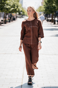 Elegant and comfortable women's linen set in chocolate brown – includes a front-pocket blouse with decorative seams and cropped wide-leg trousers with side pockets. Made from prewashed, softened 100% linen (185 g/m²), breathable and non-shrinking, designed for everyday comfort and natural style – Šokoladinės spalvos lininis kostiumėlis moterims, sudarytas iš palaidinės su kišene ir dekoratyvinėmis siūlėmis bei patrumpintų, šiek tiek platėjančių kelnių su kišenėmis. Kostiumas siūtas iš minkštinto, nebesitrau
