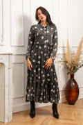 Ilga juoda moteriška suknelė iš 100 procentų viskozės su smulkiais baltais gėlių žiedeliais, lengvai pablukinto ir garinto audinio efektas suteikia natūralumo ir minkštumo pojūtį, orui pralaidus ir lengvai krentantis audinys, ilgos rankovės, priekyje sagutėmis užsegamas modelis iki pirmo atkirpimo, maža subtili stovinti apykaklė, platėjantis laisvas siluetas su lengvai raukta apačia, suknelės ilgis apie 135 cm, elegantiška ir labai patogi suknelė kasdieniam nešiojimui bei ramesnėms progoms, modelis vilki S 